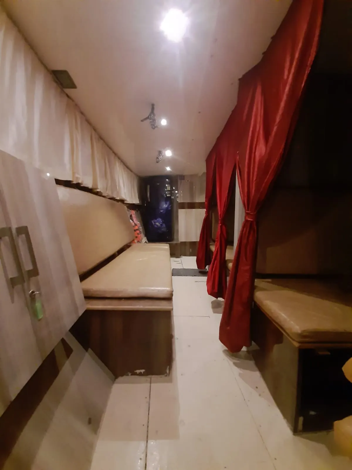 Interior passage of Max Adventures with an onboard refrigerator and curtained sleeping berths